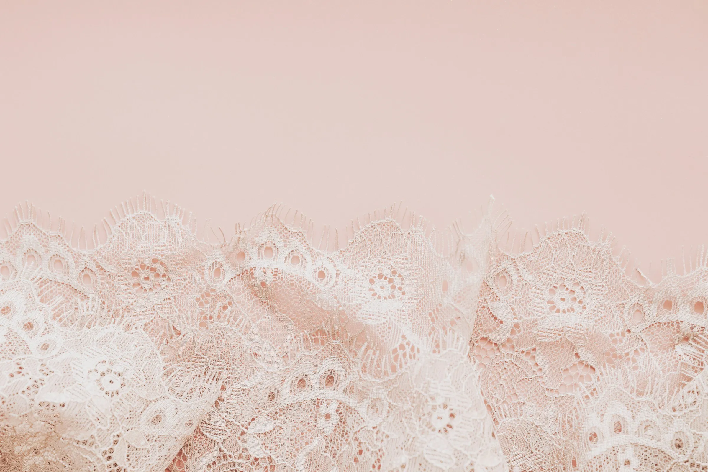 Renda branca delicada sobre um fundo rosa suave